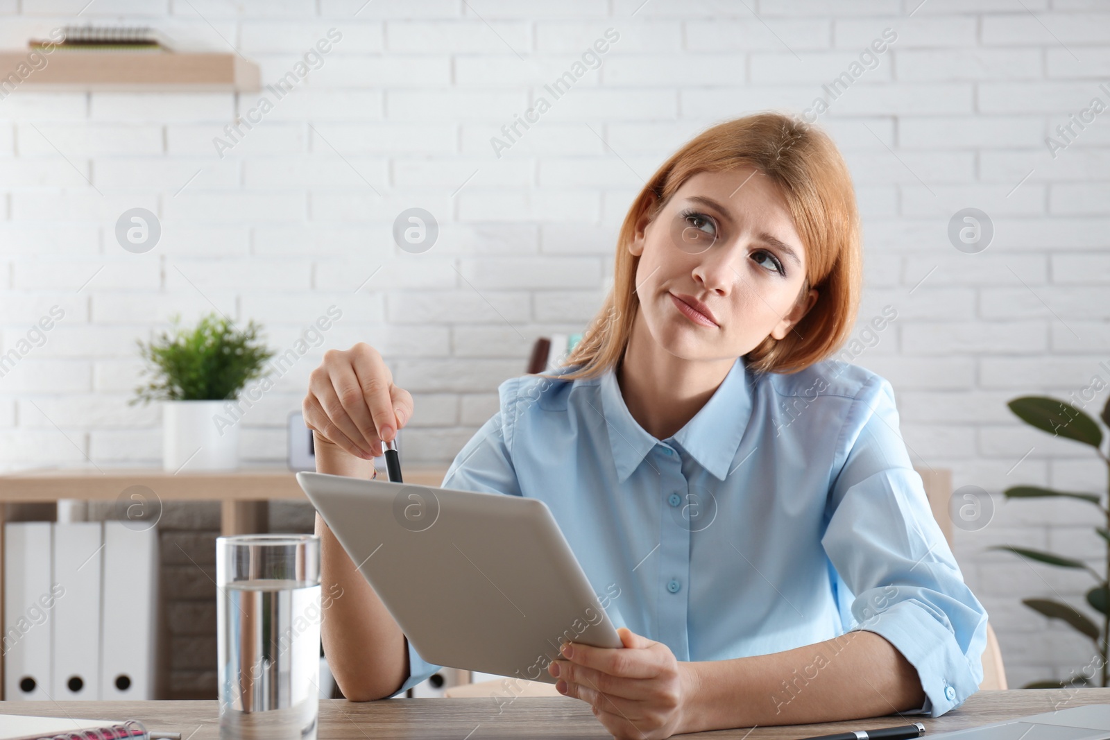 Photo of Lazy employee using tablet while resting at table in office