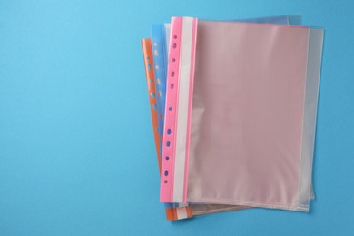 Photo of File folders with punched pockets on light blue background, flat lay. Space for text