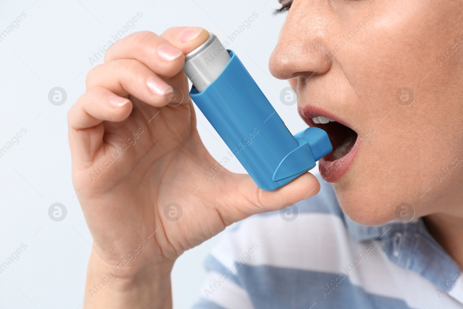 Photo of Woman using asthma inhaler on white background, closeup