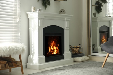 Photo of Bright living room interior with artificial fireplace and firewood in basket