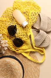 String bag and different beach accessories on beige background, top view