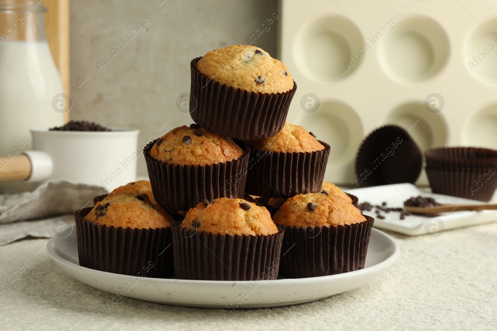 Photo of Delicious sweet muffins with chocolate chips on light textured table