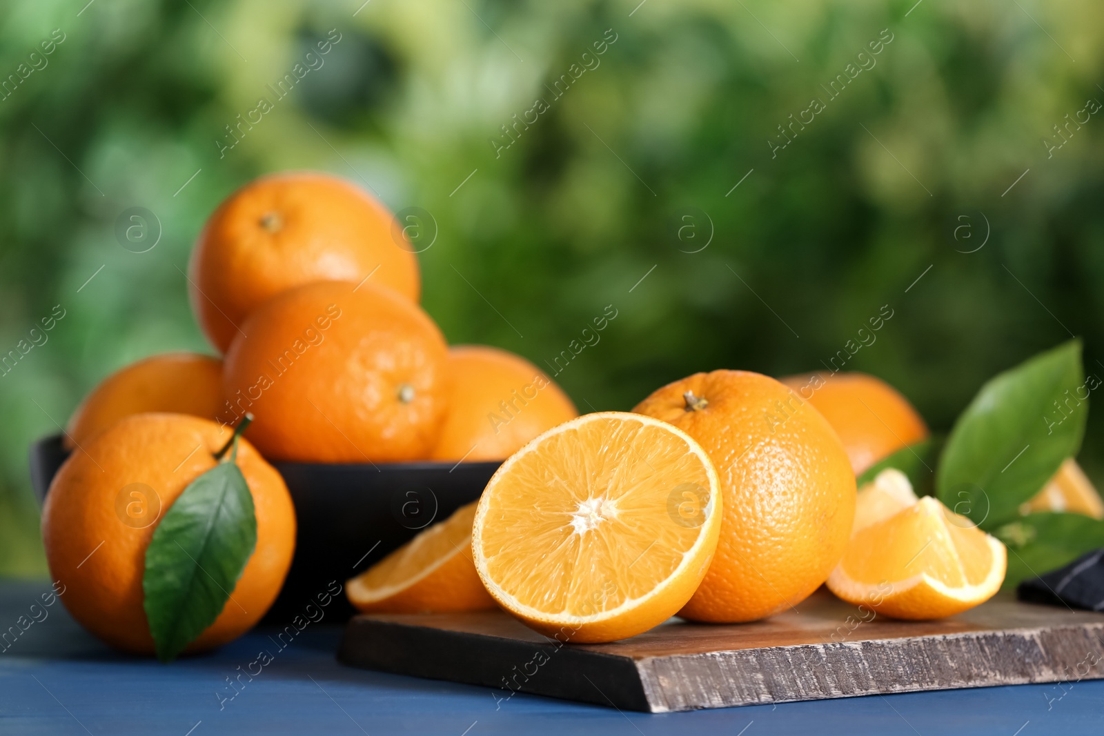 Photo of Fresh ripe oranges on blue wooden table against blurred background. Space for text