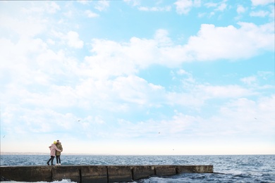 Lovely young couple walking on pier near sea