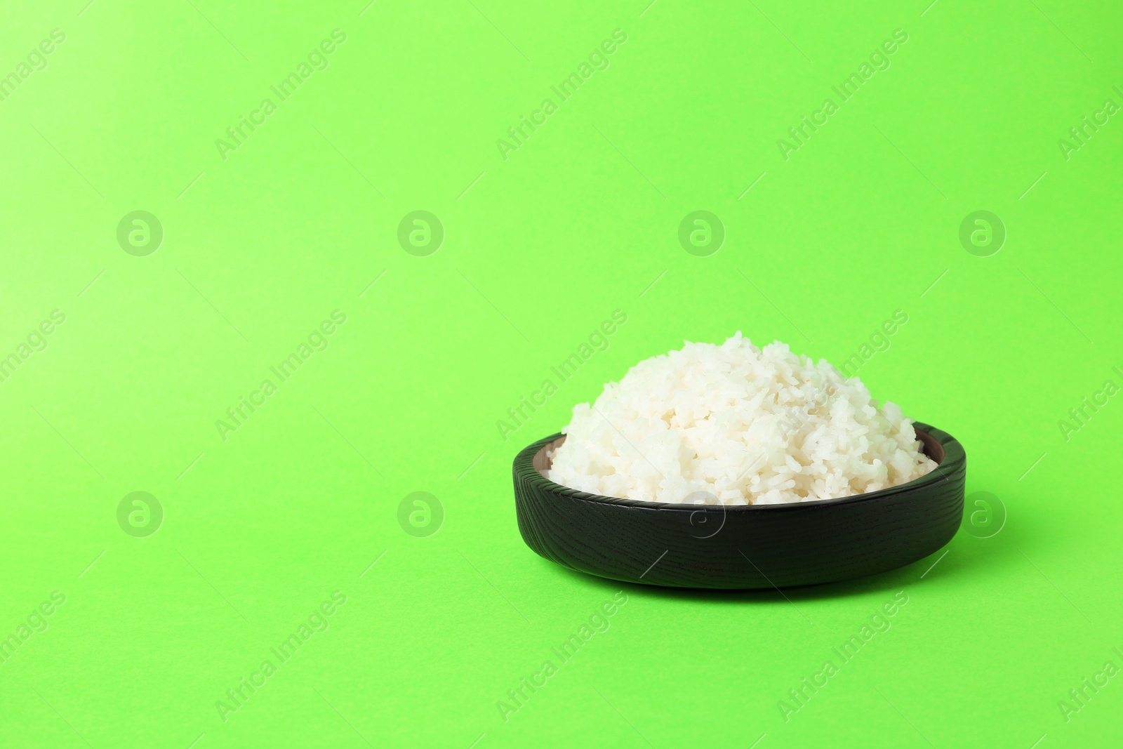 Photo of Bowl of boiled rice on color background. Space for text