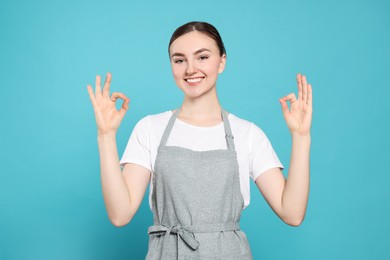 Photo of Beautiful young woman in clean apron with pattern on light blue background