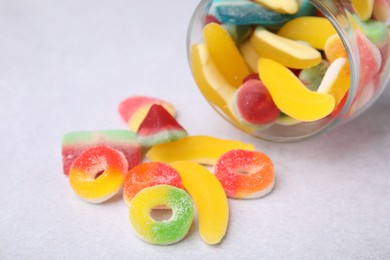 Photo of Tasty jelly candies and jar on light grey table, closeup