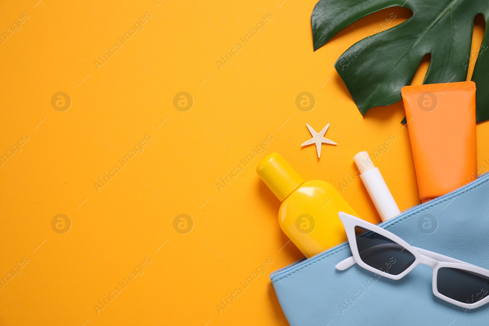 Photo of Flat lay composition with sun protection products and beach accessories on orange background. Space for text