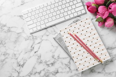 Stylish workplace with fragrant peonies on marble table, flat lay. Space for text