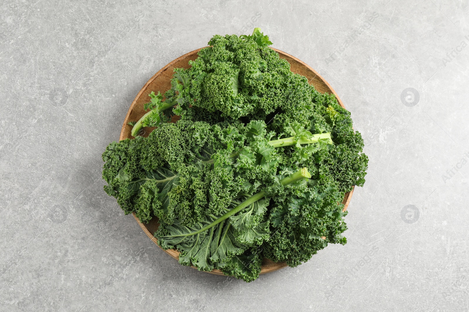 Photo of Fresh kale leaves on light grey table, top view