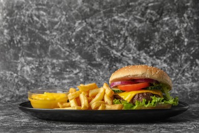 Photo of Delicious burger and french fries on grey textured background