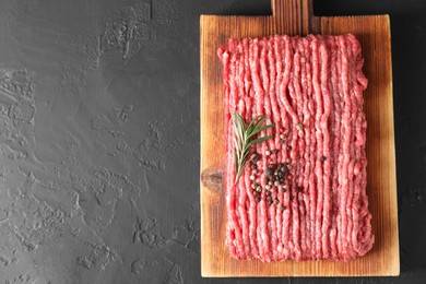 Photo of Raw ground meat, rosemary and peppercorns on black table, top view. Space for text