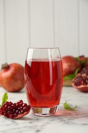 Photo of Tasty pomegranate juice in glass and fresh fruits on white marble table