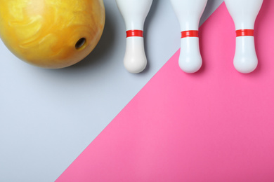 Photo of Bowling ball and pins on color background, flat lay. Space for text