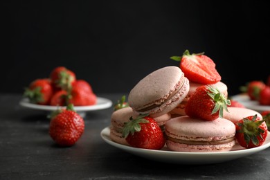 Photo of Delicious macarons and strawberries on black table