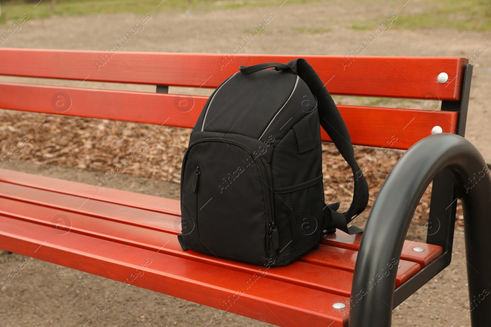 Photo of Stylish black backpack for camera on wooden bench outdoors