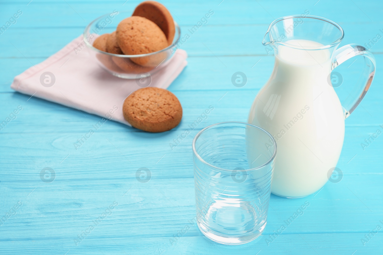 Photo of Glassware with milk and oatmeal cookies on wooden table. Fresh dairy product