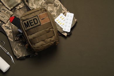 Photo of First aid kit and military uniform on khaki background, flat lay. Space for text