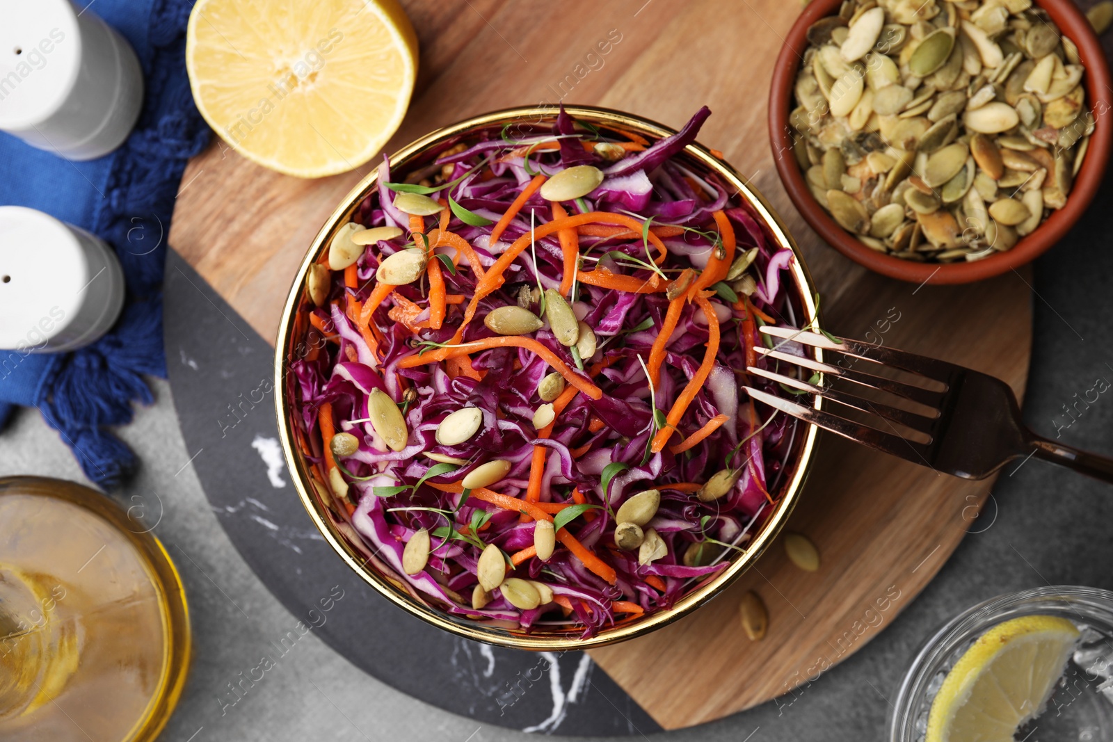Photo of Eating tasty salad with red cabbage and pumpkin seeds on table, flat lay