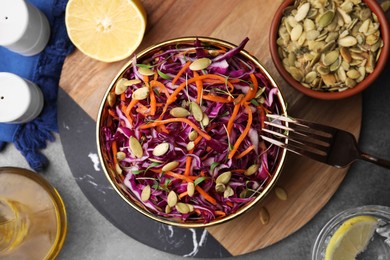 Eating tasty salad with red cabbage and pumpkin seeds on table, flat lay