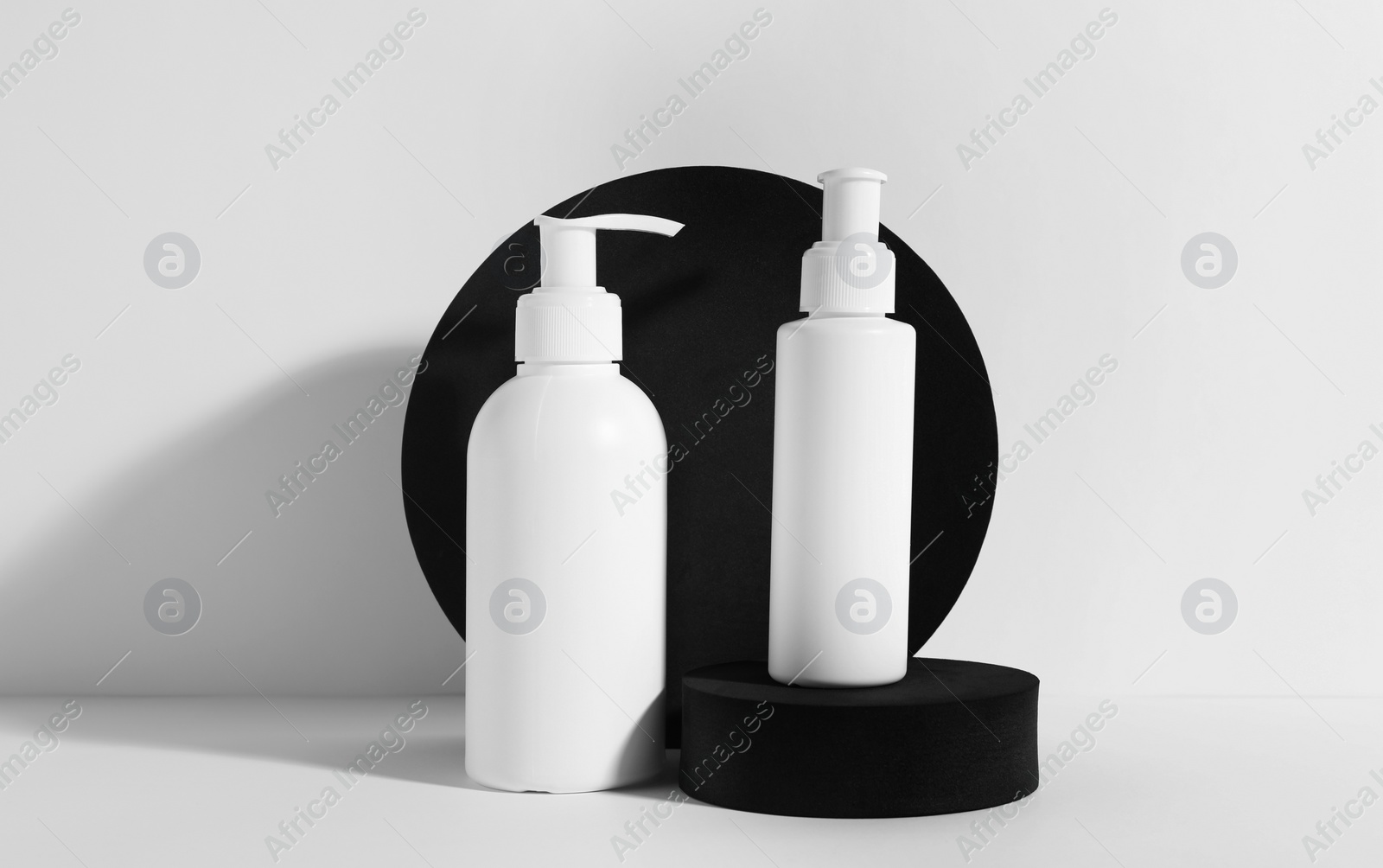 Photo of Bottles with different cosmetic products and podiums on white background