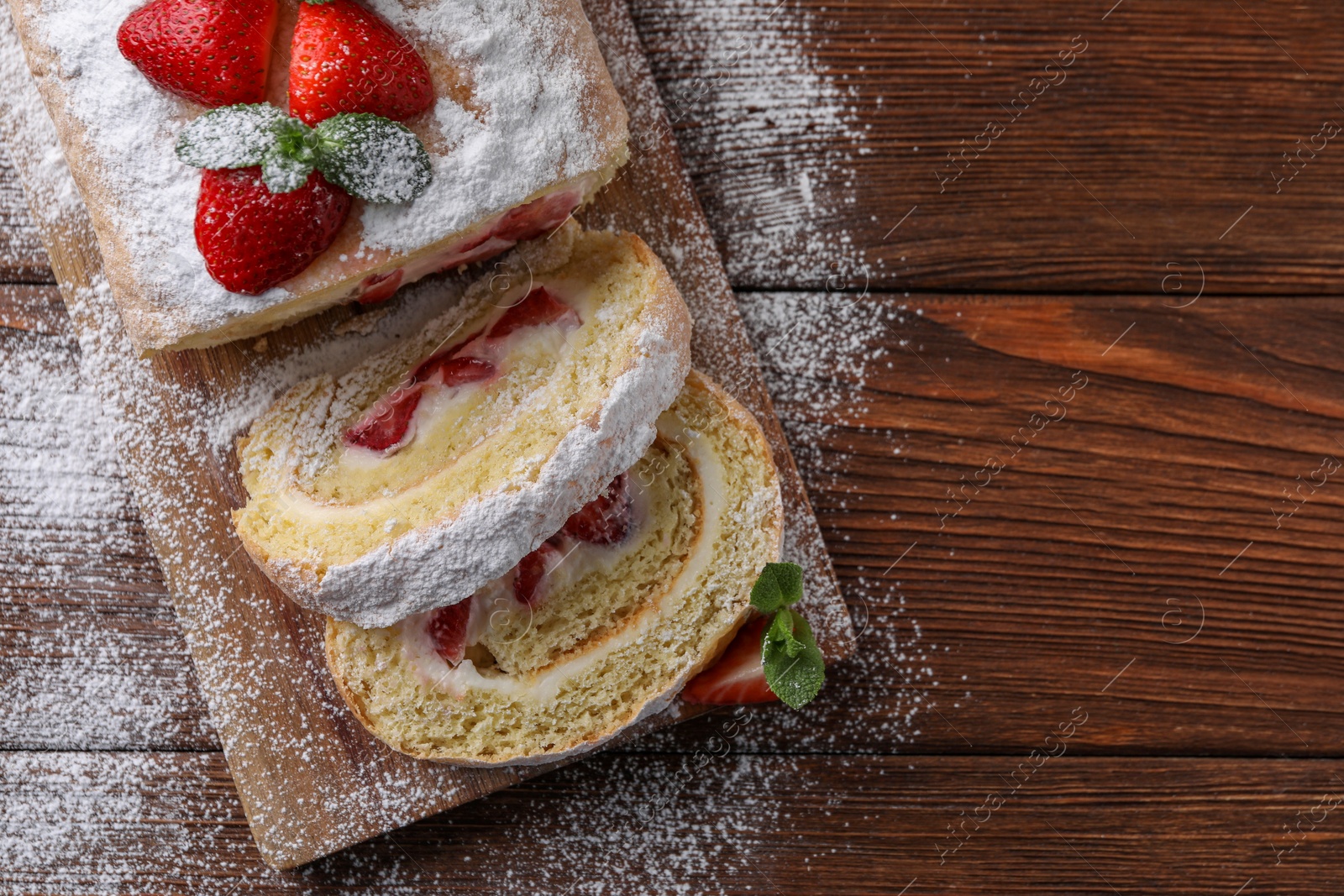 Photo of Pieces of delicious cake roll with strawberries and cream on wooden table, top view. Space for text