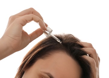 Photo of Mature woman applying oil onto hair on white background, closeup. Baldness problem