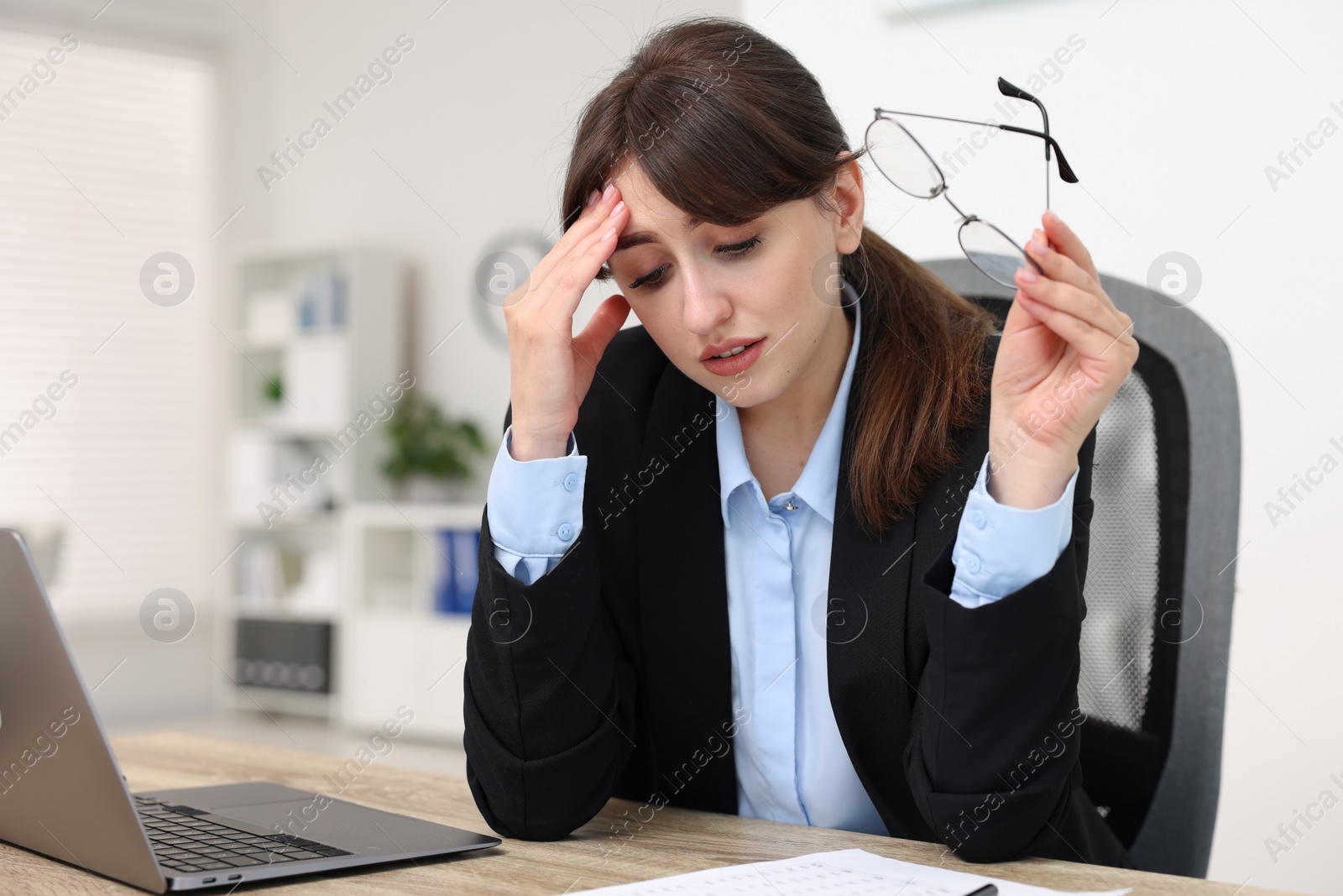 Photo of Overwhelmed woman with glasses at table in office