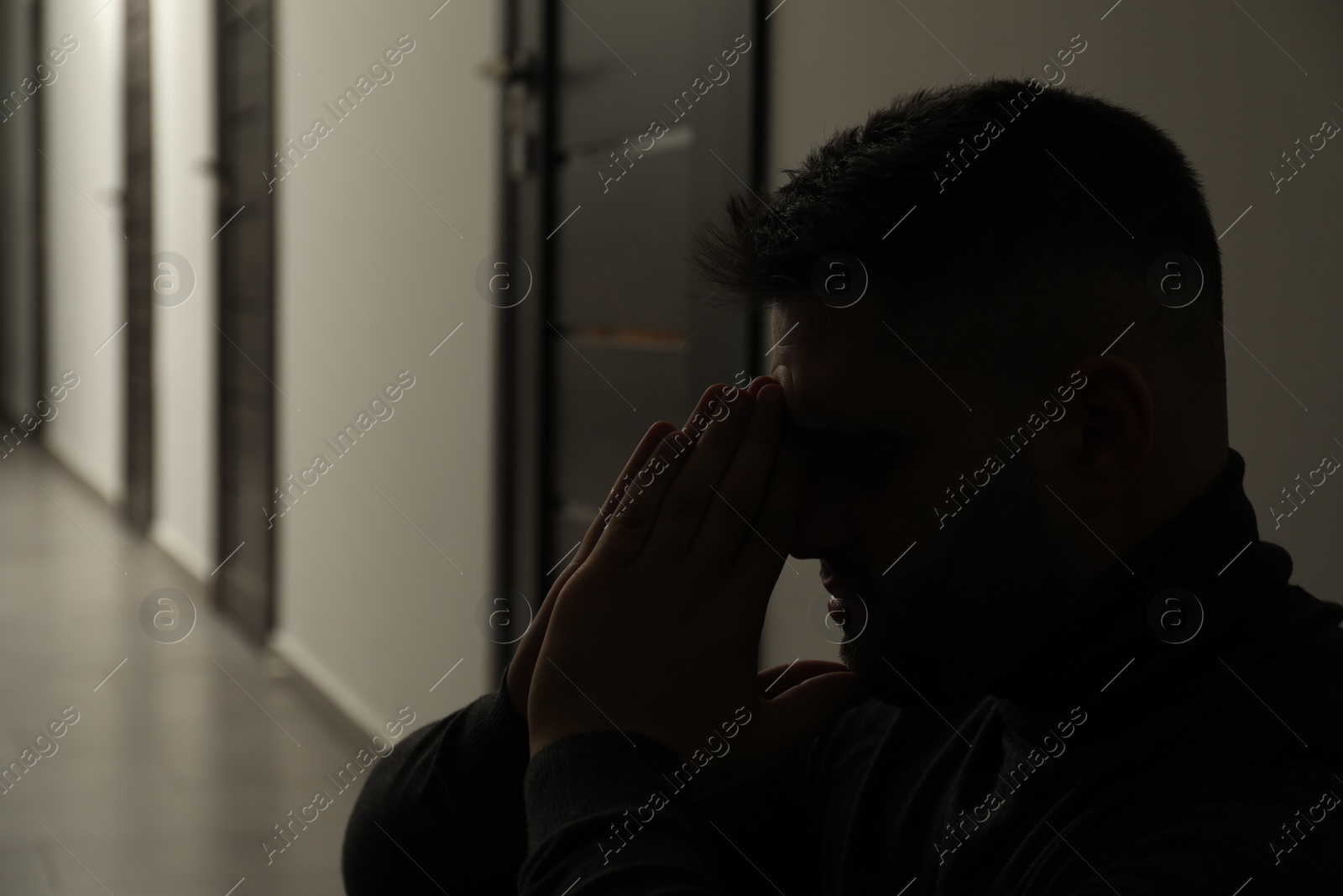 Photo of Silhouette of sad man in hall. Space for text