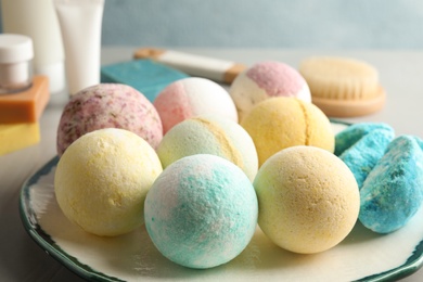 Plate with colorful bath bombs on table, closeup