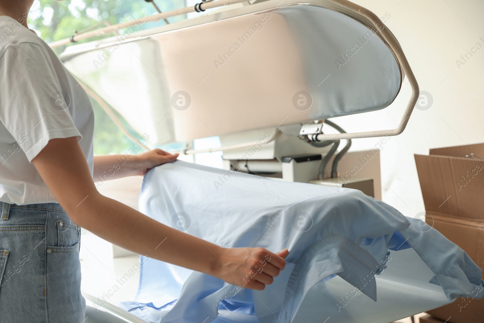 Photo of Female worker using ironing press in dry-cleaning, closeup