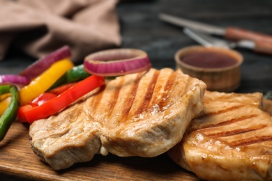 Photo of Grilled steaks with garnish on wooden board, closeup. Tasty meat