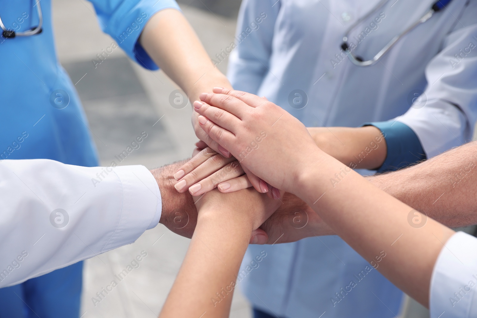 Photo of Team of medical doctors putting hands together indoors, closeup