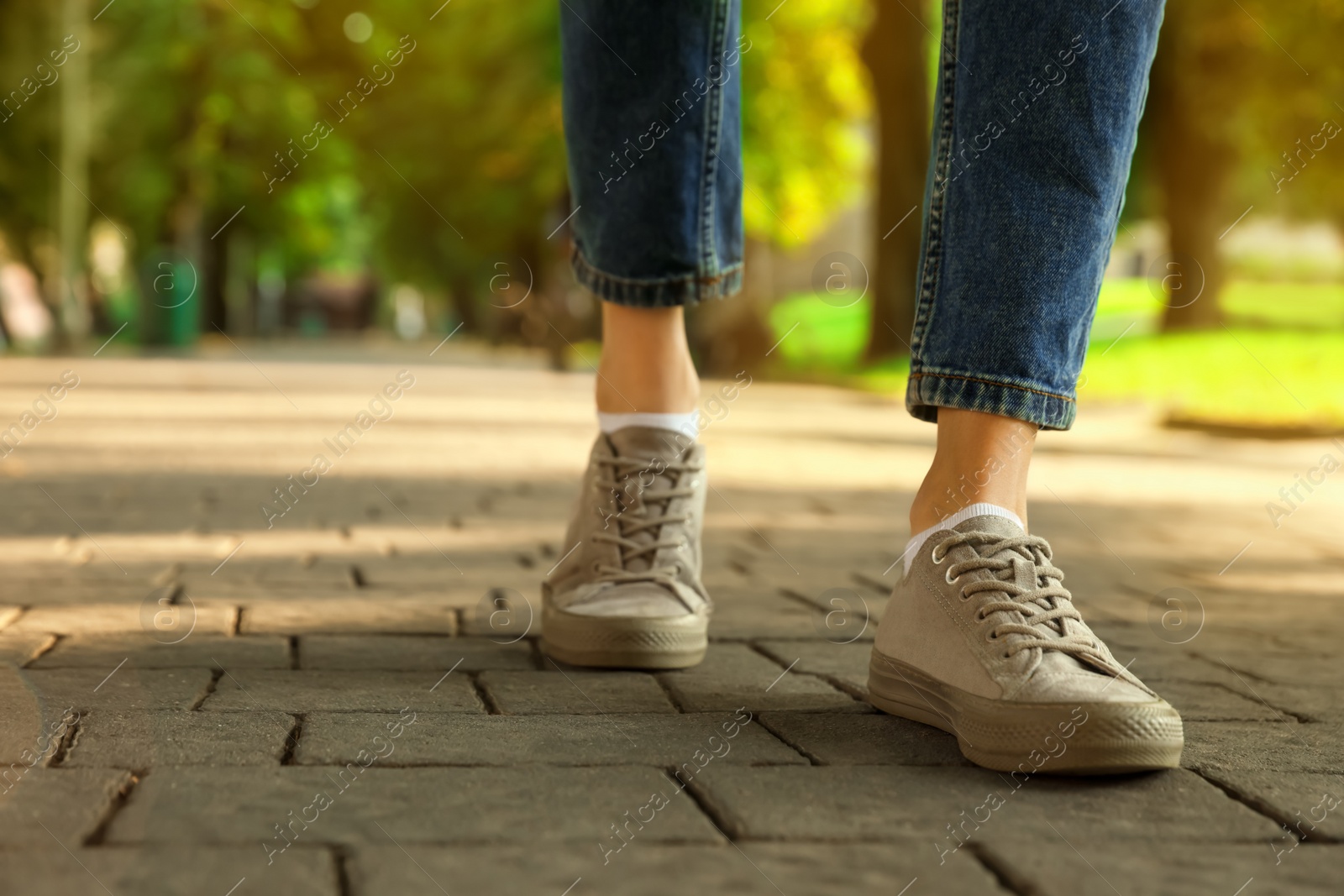 Photo of Woman in stylish sneakers walking on city street, closeup