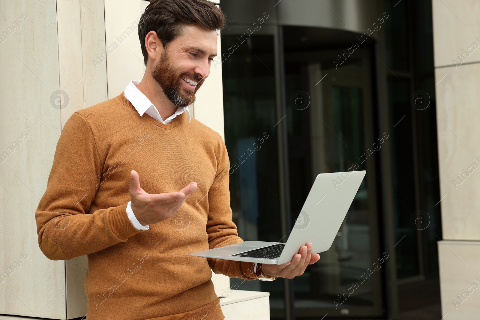 Photo of Handsome man with laptop near building on city street