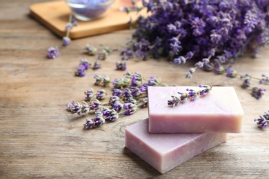 Handmade soap bars with lavender flowers on brown wooden table. Space for text
