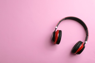 Wireless headphones on color background, top view. Space for text