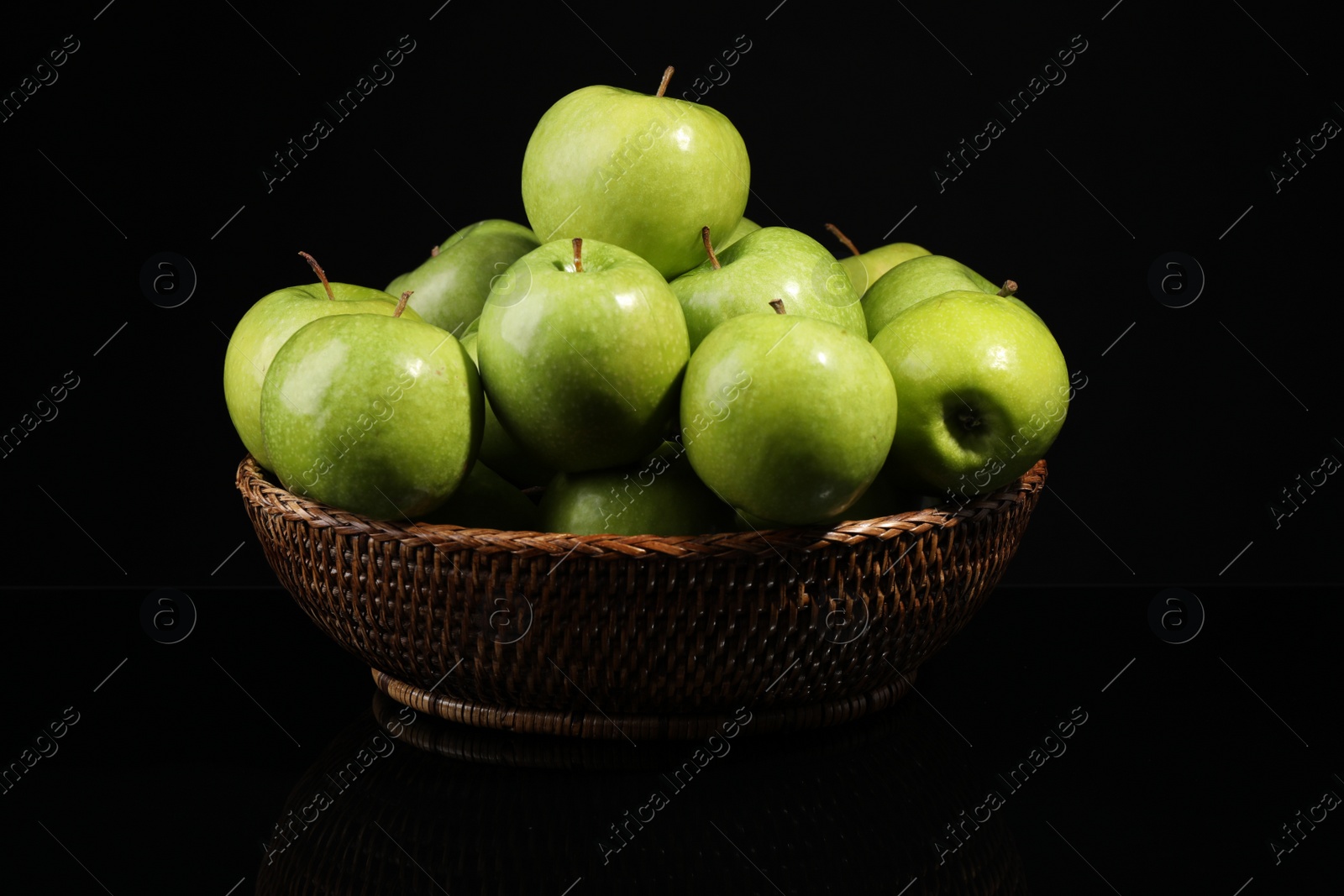 Photo of Bowl with green apples on black background