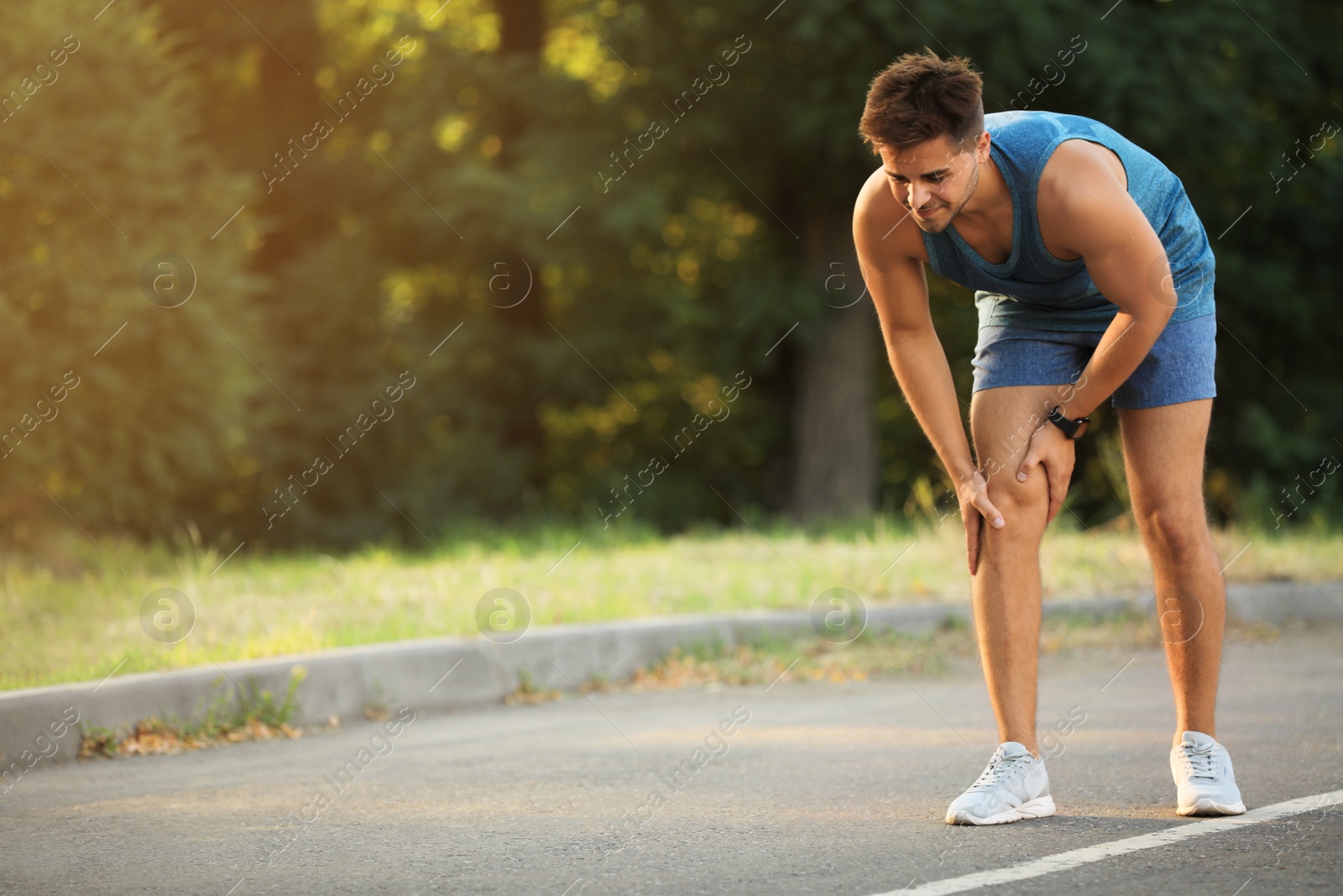 Photo of Young man in sportswear having knee problems in park