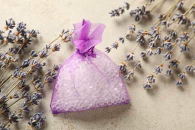 Photo of Scented sachet with aroma beads and dried lavender on grey table, flat lay