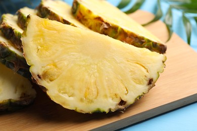 Photo of Slices of ripe juicy pineapple on light blue table, closeup