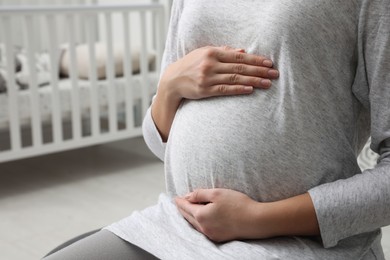 Photo of Pregnant woman in baby room, closeup view. Space for text