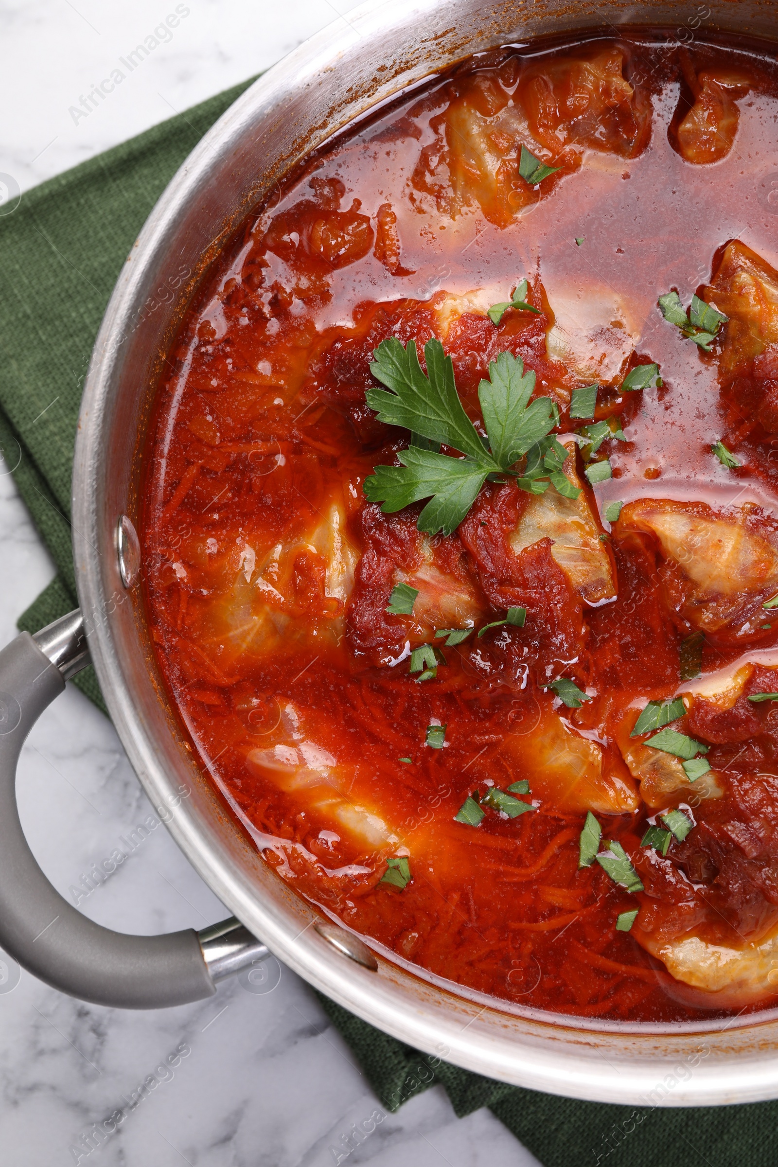 Photo of Delicious stuffed cabbage rolls cooked with homemade tomato sauce in pot on white marble table, top view