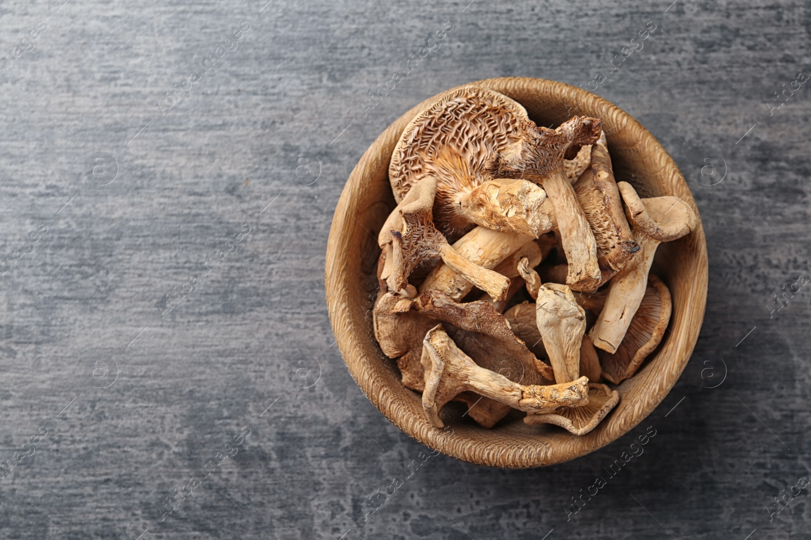 Photo of Bowl of dried mushrooms on color background, top view. Space for text