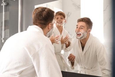 Photo of Dad and son with shaving foam on faces in bathroom