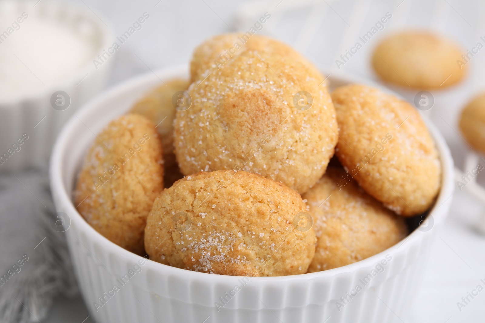 Photo of Tasty sugar cookies in bowl on white table, closeup