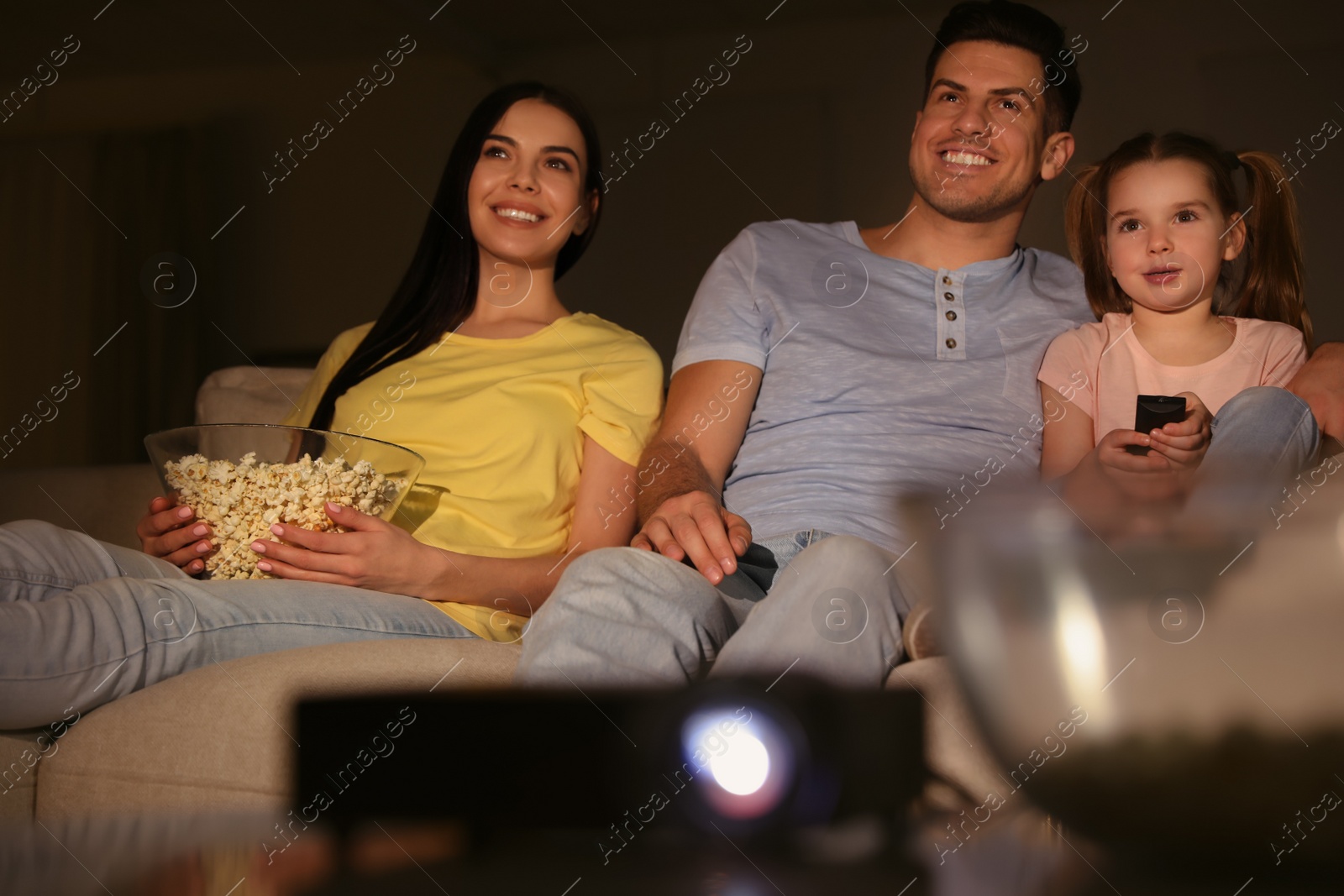 Photo of Family watching movie with popcorn on sofa at night