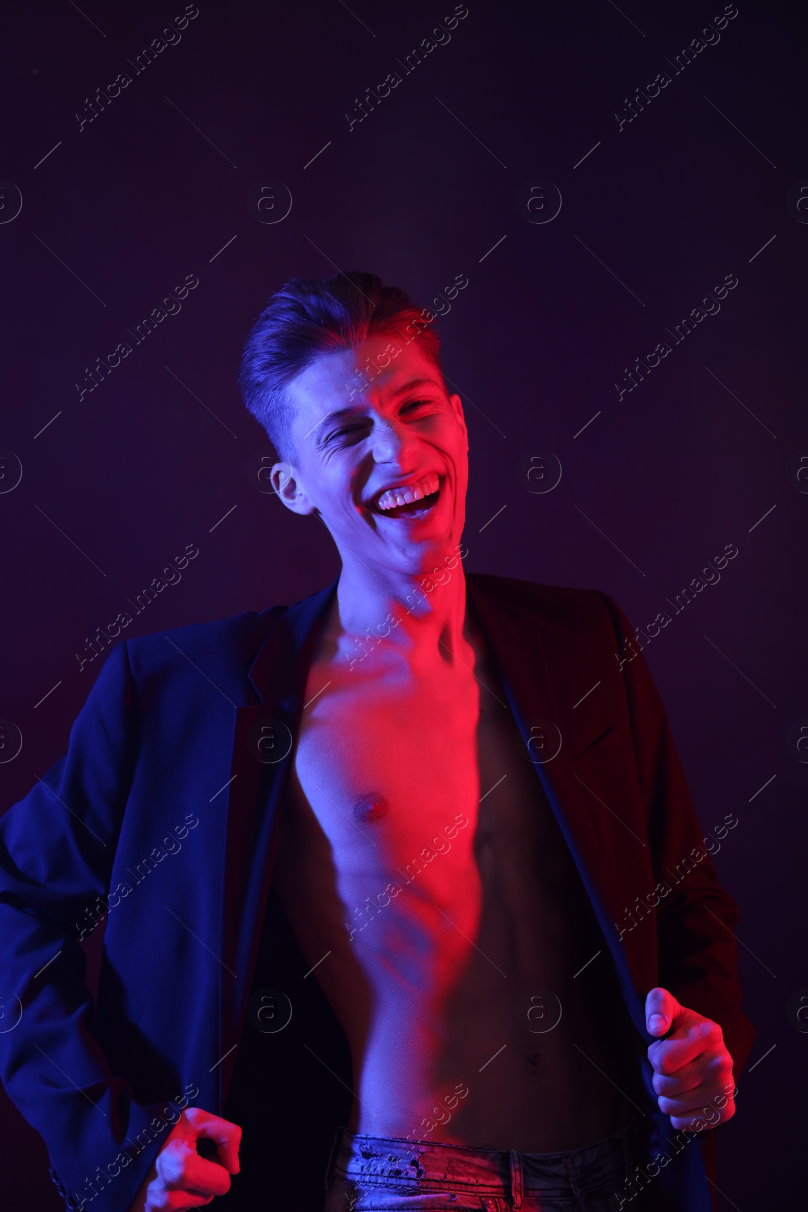 Photo of Sexy young man on dark background in neon lights