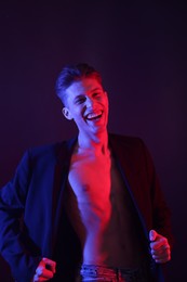 Photo of Sexy young man on dark background in neon lights