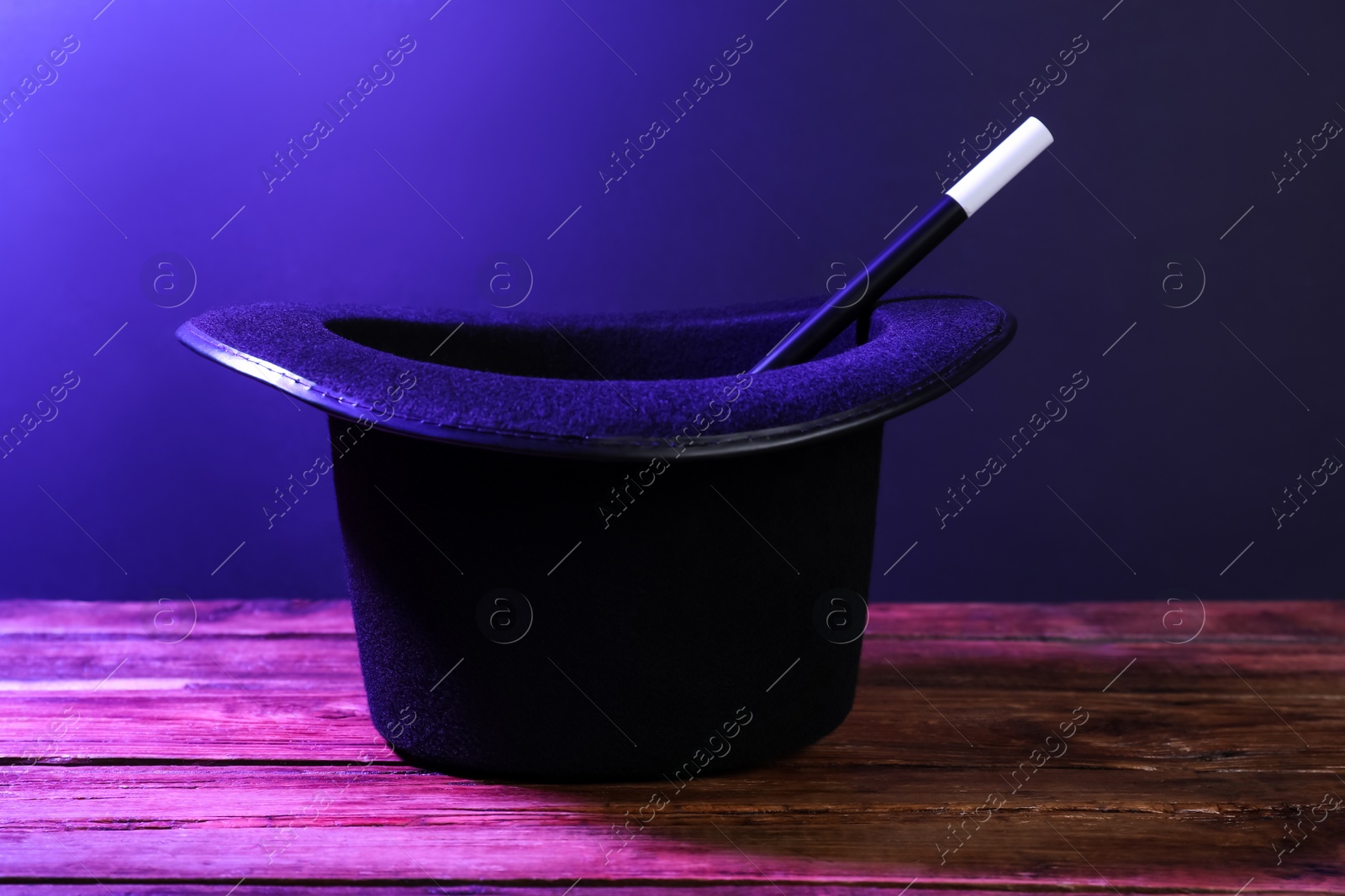 Photo of Black top hat and wand on wooden table. Magician equipment